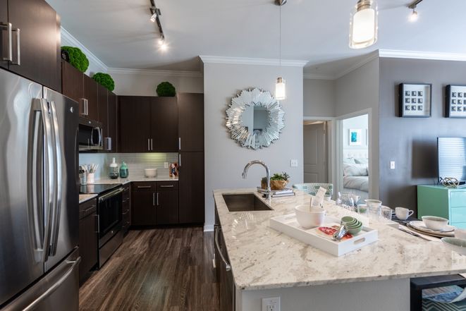 A modern kitchen with a marble countertop island and stylish lighting.
