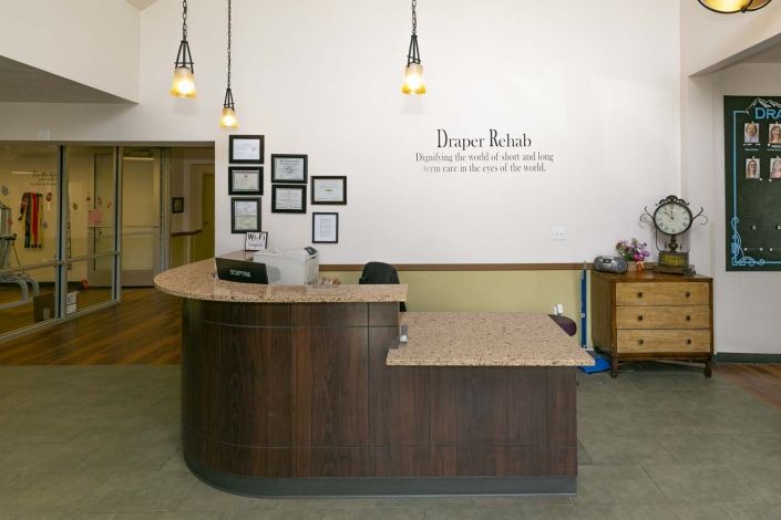 A reception area with a curved wooden desk, framed wall art, and pendant lighting.