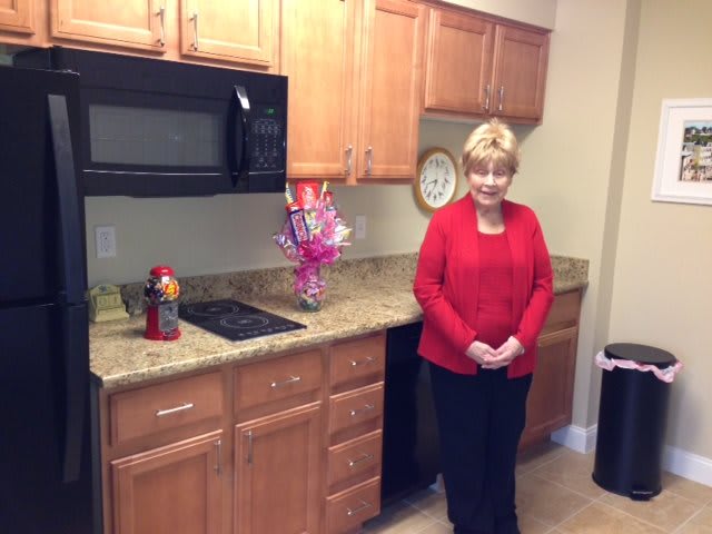 A woman standing in a kitchen with wooden cabinets and modern appliances.