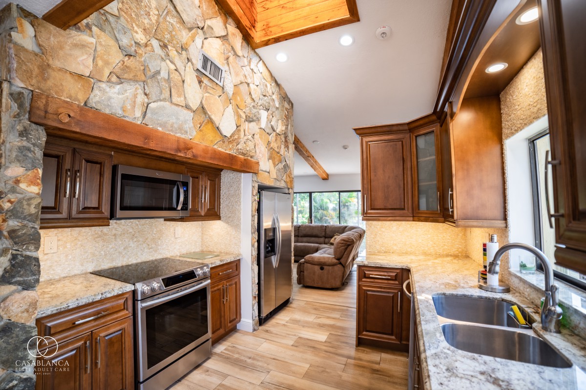 A modern kitchen with wooden cabinets, stone wall accents, and stainless steel appliances.