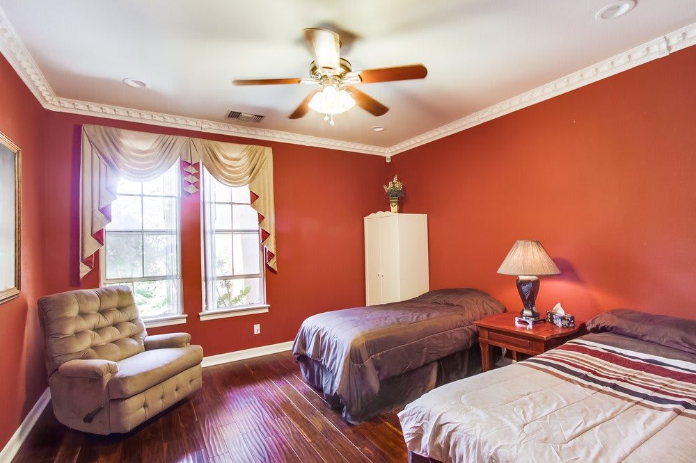 A cozy bedroom with twin beds, red walls, and natural light from a large window.