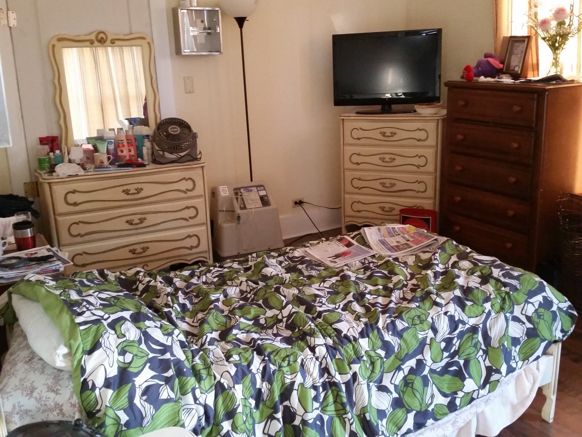 A cozy bedroom with a colorful bedspread, TV, and dresser.
