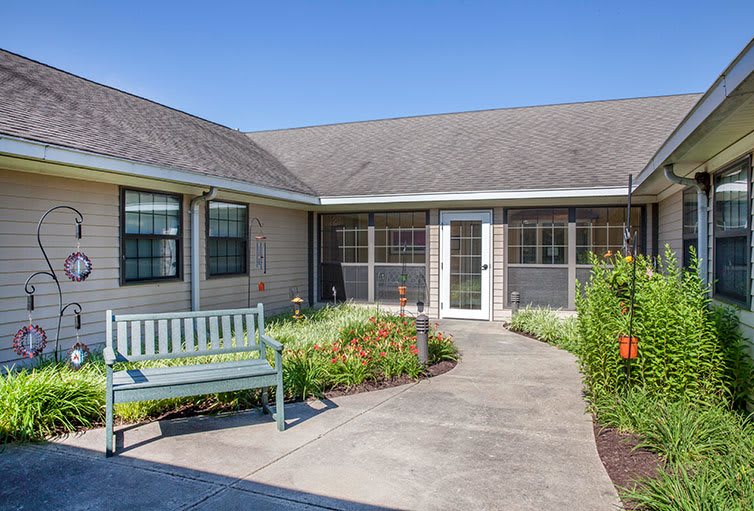 A quaint courtyard featuring a garden with a pathway leading to a building entrance.