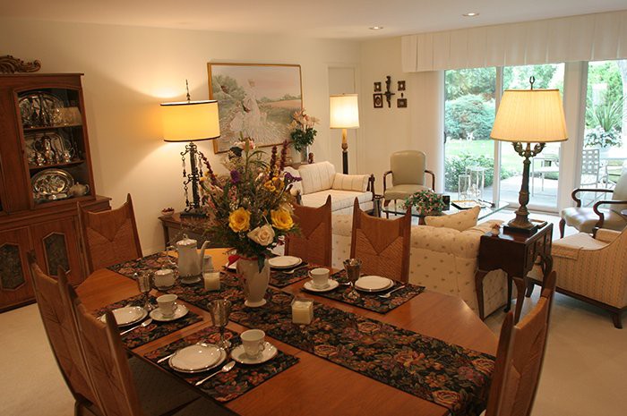 A warmly lit dining and living area with a beautifully set table, cozy seating, and tasteful decor.