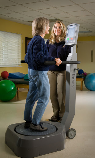 A therapist assists a patient during a rehabilitation exercise using specialized equipment.