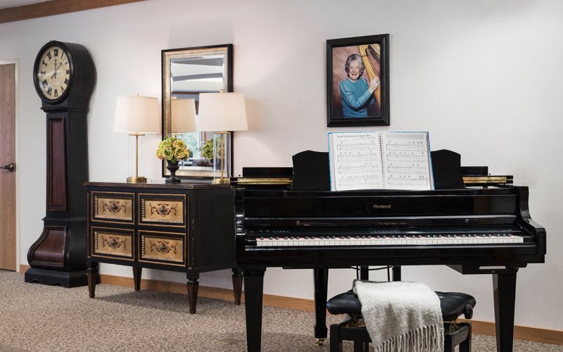 A cozy living room featuring a grand piano, decorated with elegant furniture and artwork.