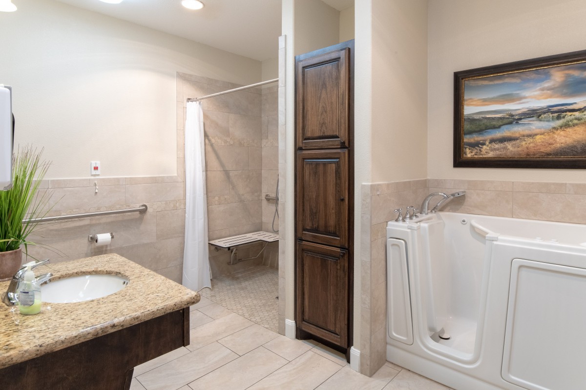 A modern bathroom featuring a walk-in tub and accessible shower with beige tile flooring.