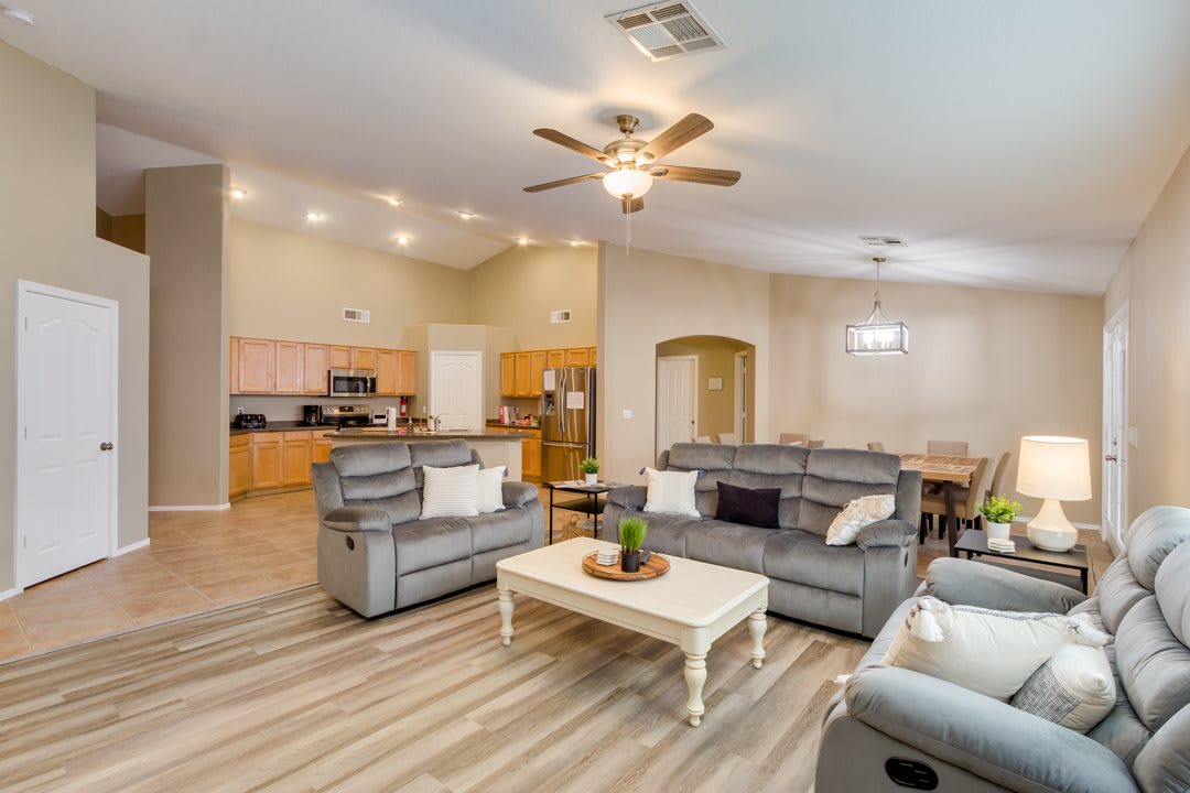 A modern open floor plan living space with a comfortable seating area, adjacent kitchen, and dining area.