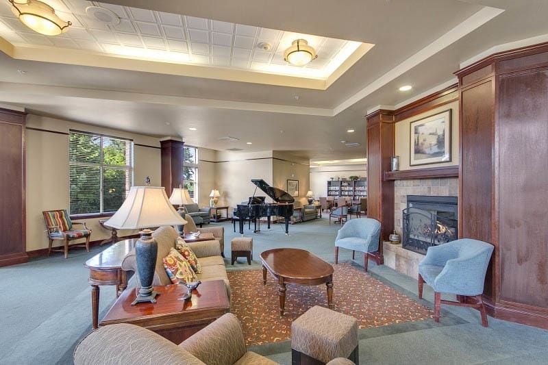 A spacious lounge with comfortable seating, featuring a grand piano and a cozy fireplace.