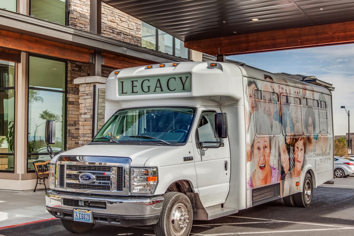 A white bus labeled 'Legacy' parked outside a building.