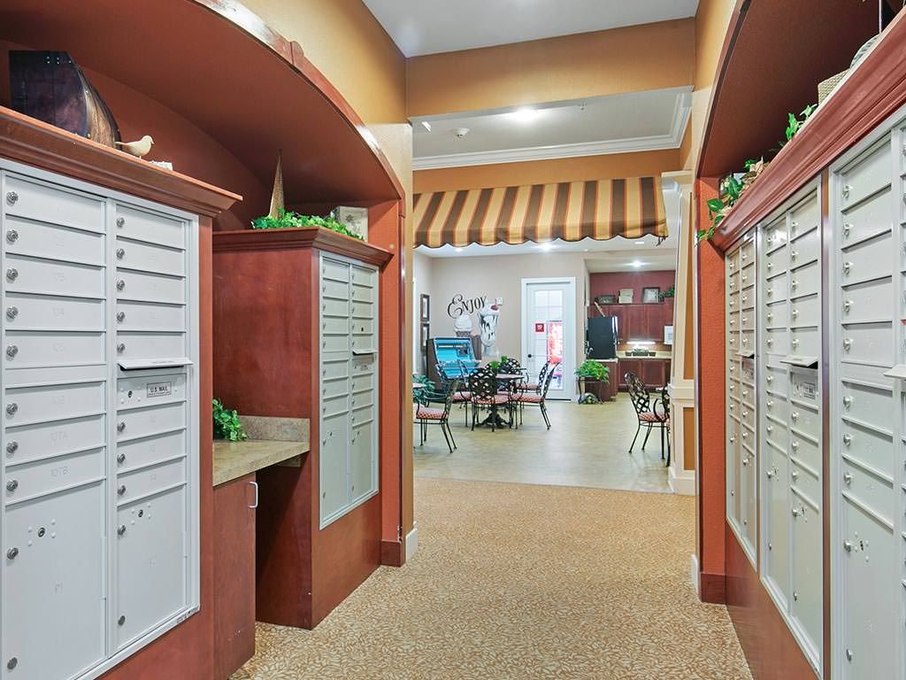 A bright and organized community mailroom with multiple mail lockers and a seating area.