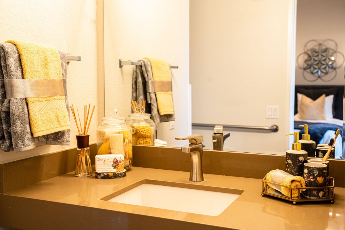 A modern bathroom with a sink, mirror, and neatly arranged accessories.