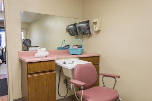 A cozy hair salon setup featuring a comfortable chair, vanity area, and mirror.