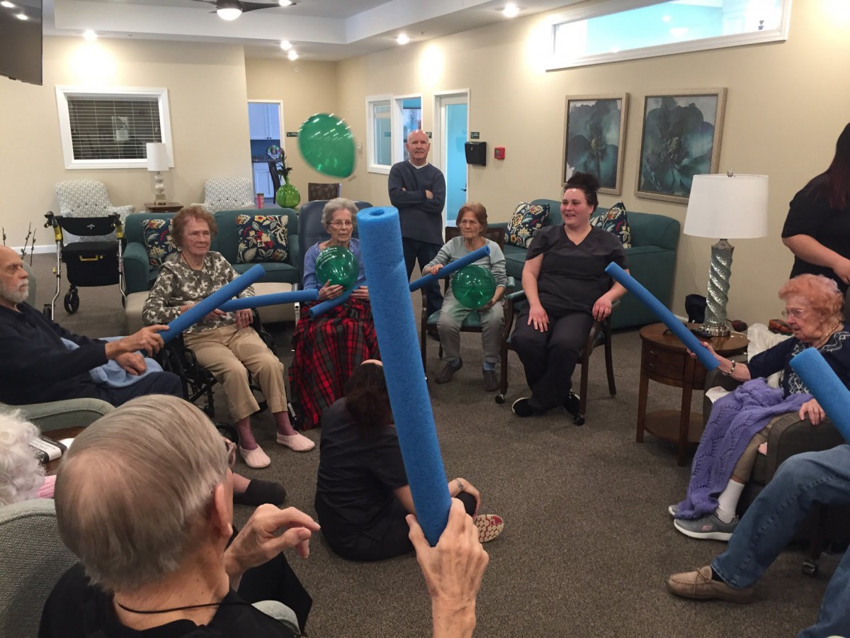 Elderly individuals participating in a group exercise session using foam noodles in a retirement home.