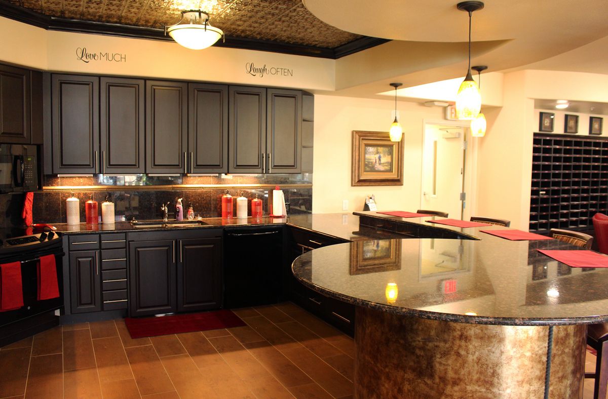 A modern kitchen interior featuring dark cabinets and a large countertop under warm lighting.