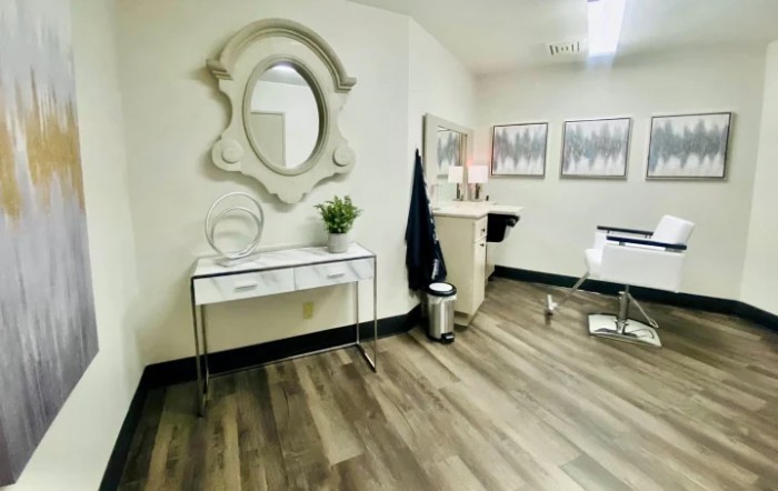 A modern interior space with minimalist decor, featuring a mirror, hardwood floors, and a barber chair.