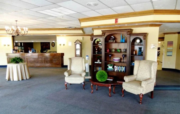 A cozy hotel lobby with armchairs and a decorative bookshelf.
