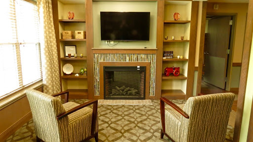 A cozy living room setup featuring a fireplace, television, and decorative shelves.