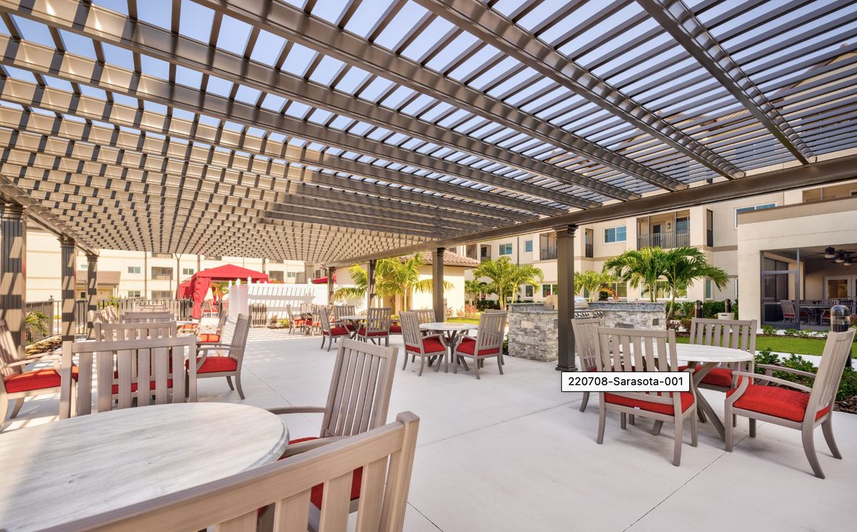 A modern outdoor patio area with wooden pergolas providing shade over tables and chairs.
