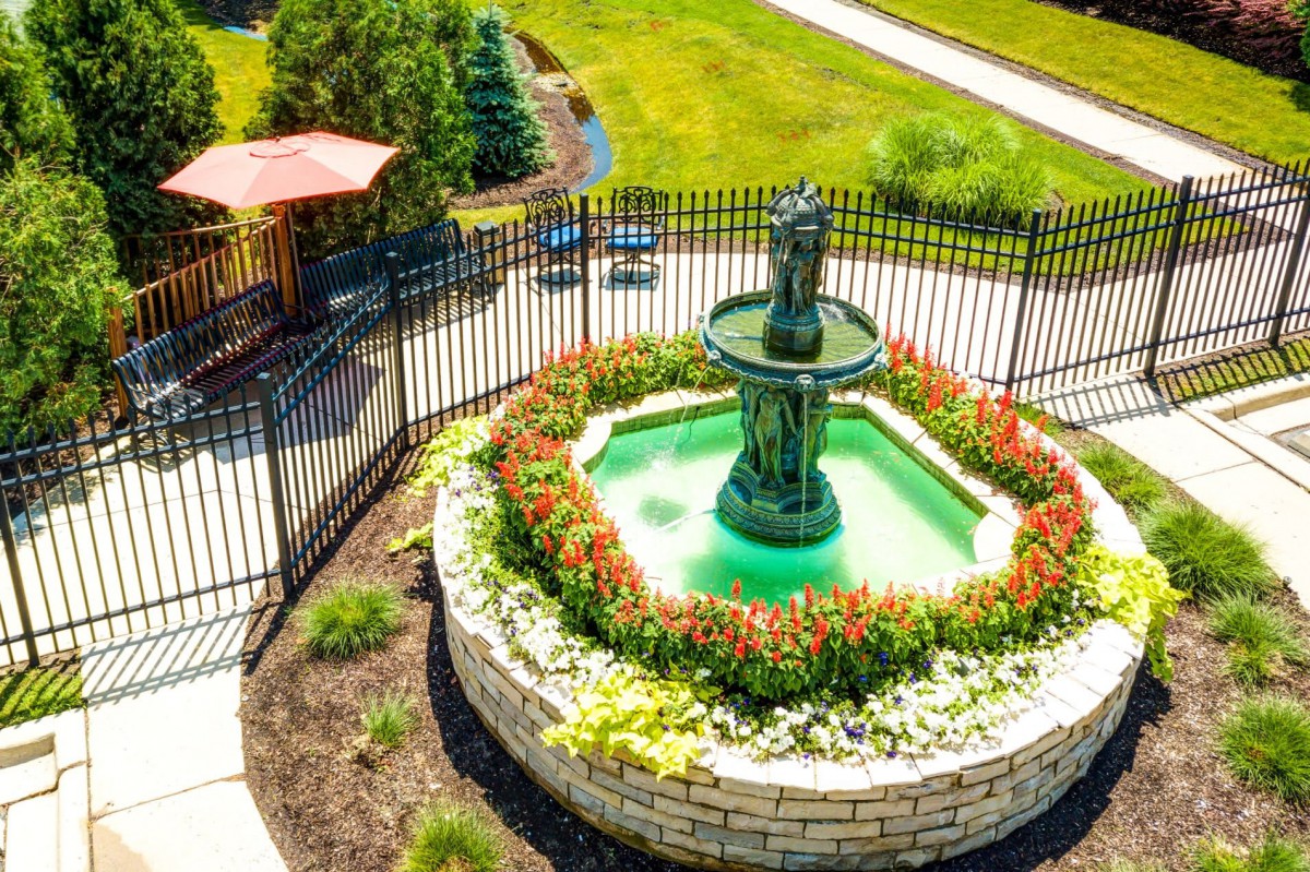 A beautifully landscaped garden featuring a central fountain surrounded by vibrant flowers.