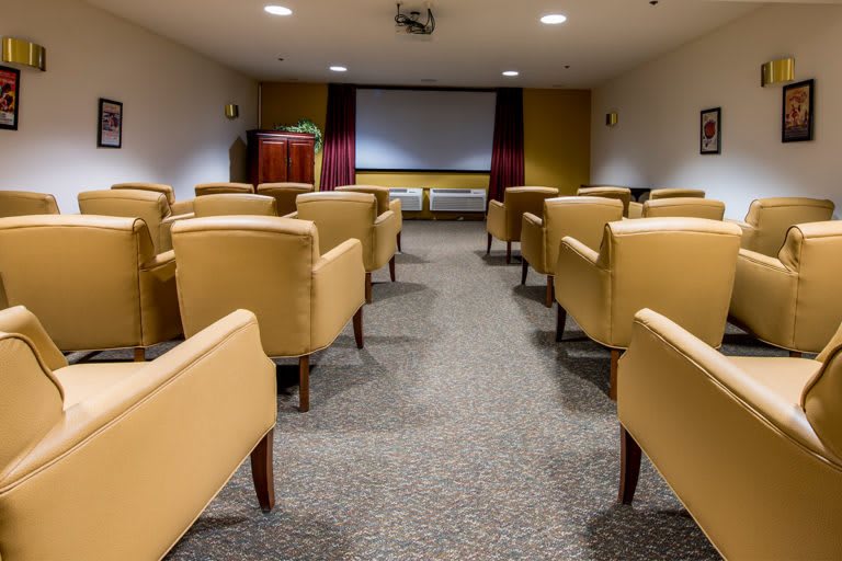 A cozy indoor movie theater with comfortable seating and a large projector screen.