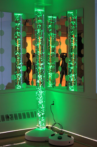 A vibrant display of green lights creates an artistic atmosphere as silhouettes are reflected in the background.