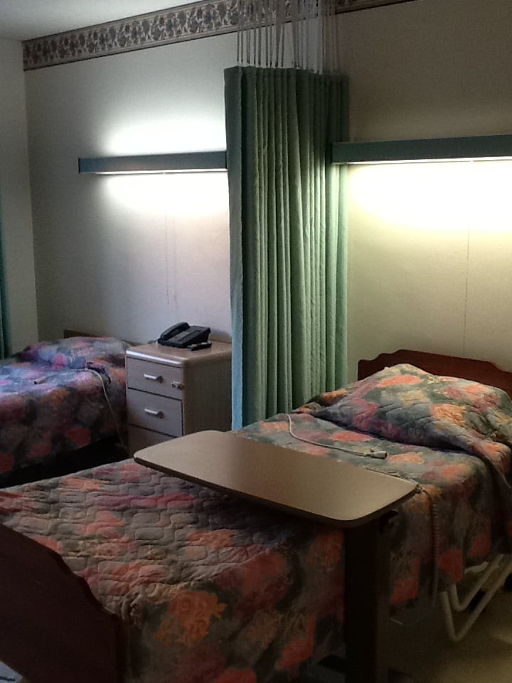 A hospital room with two beds separated by a curtain.
