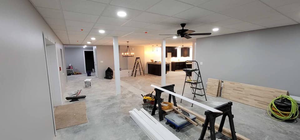 An unfinished basement undergoing renovation, with tools and equipment scattered around the open space.