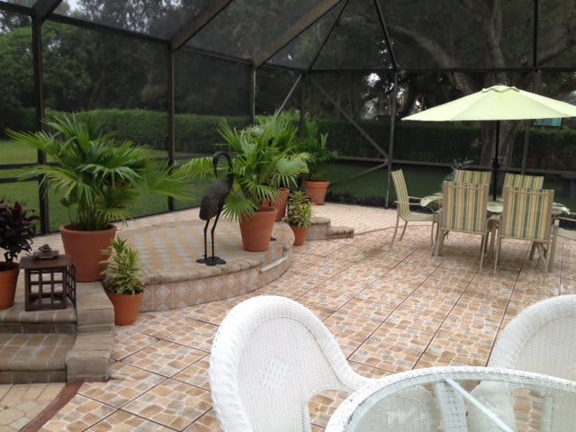 A cozy patio with potted plants and outdoor furniture under a screened enclosure.