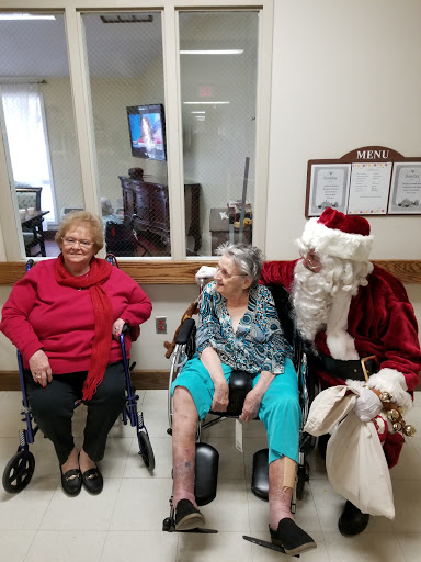 Residents of a care facility enjoy a cheerful visit from Santa Claus during the holiday season.