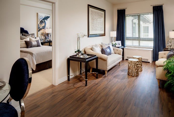 Modern apartment living area with a connected bedroom featuring stylish furniture and wood flooring.