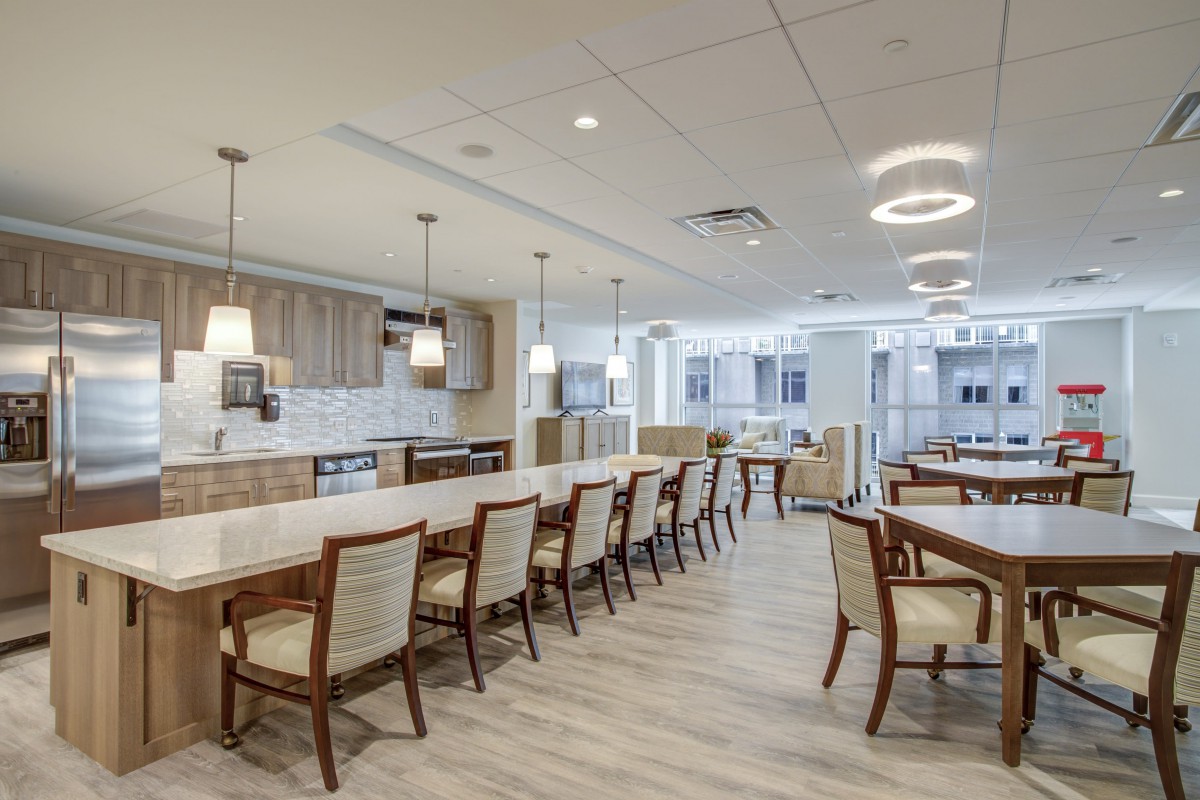 A modern and spacious kitchen and dining area with elegant lighting fixtures and seating.