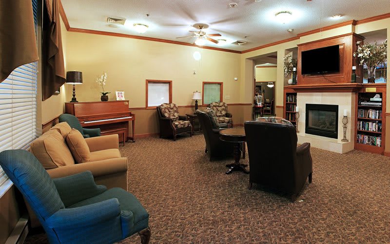 A cozy living room with comfortable seating, a fireplace, and a piano.