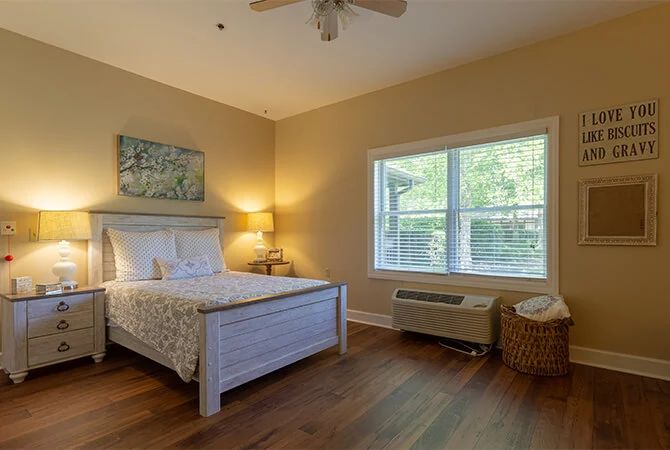 A cozy bedroom with a large window and warm lighting.