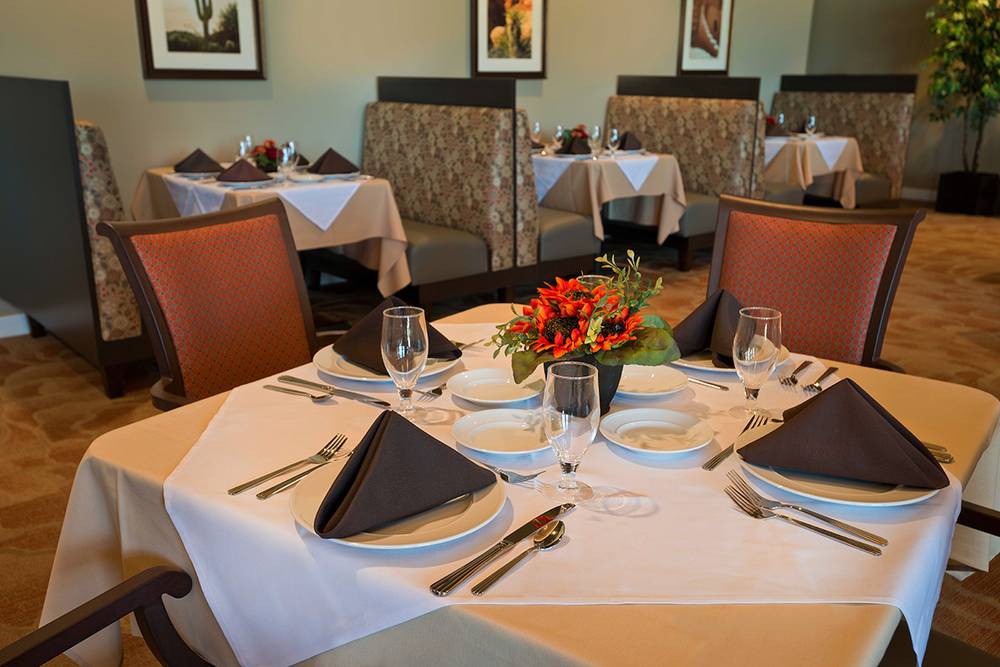 A elegantly set dining table in a restaurant with flowers and glasses.