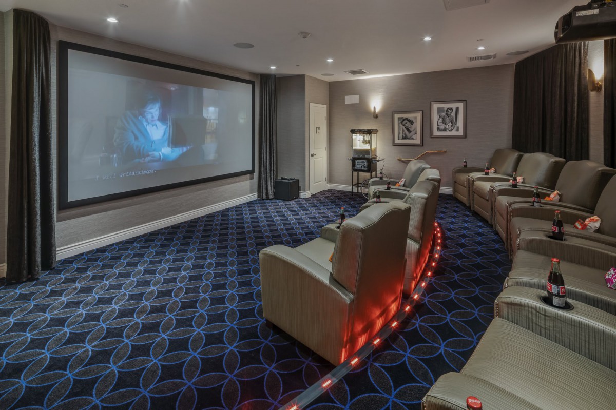A modern home theater room with recliner seating and a large projector screen.