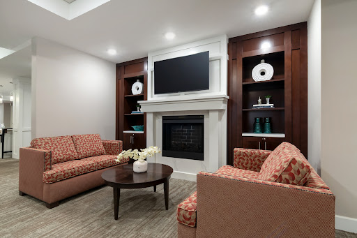 A cozy and elegantly designed living room featuring comfortable seating, a decorative fireplace, and stylish shelving.
