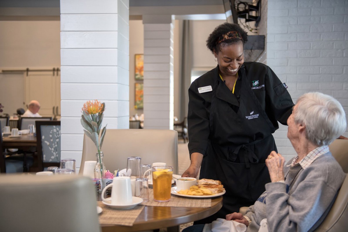 A server delivers a meal to a customer in a restaurant setting.