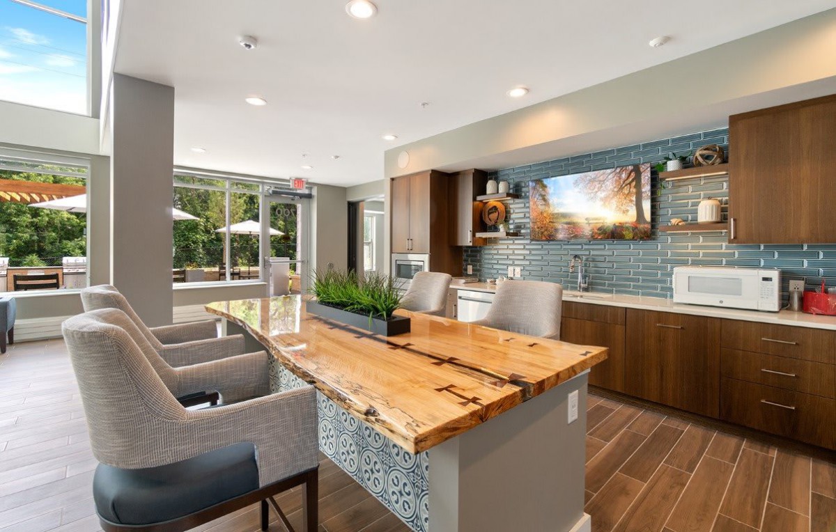 A modern kitchen with a wooden countertop and bar seating, featuring an open and well-lit design.