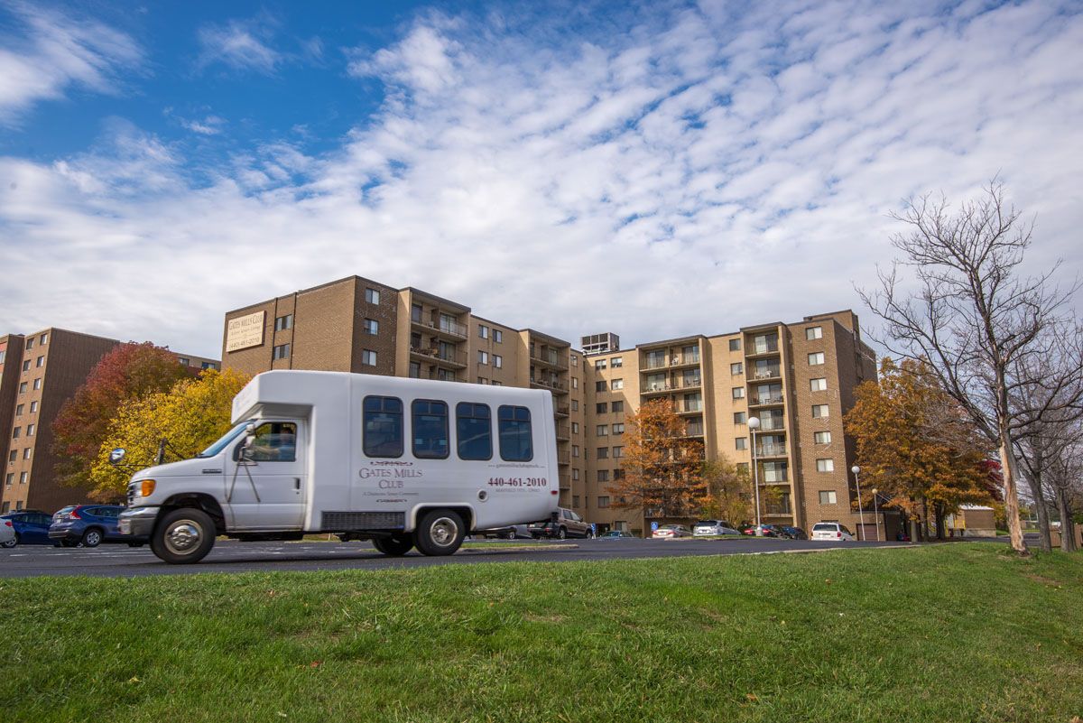 A white van parked in front of a suburban apartment building on a cloudy day.