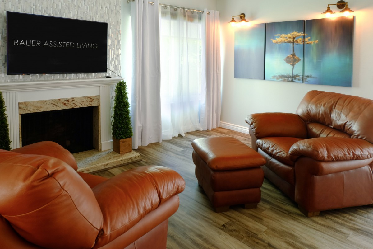 A cozy living room featuring leather furniture, a fireplace, and decorative artwork.