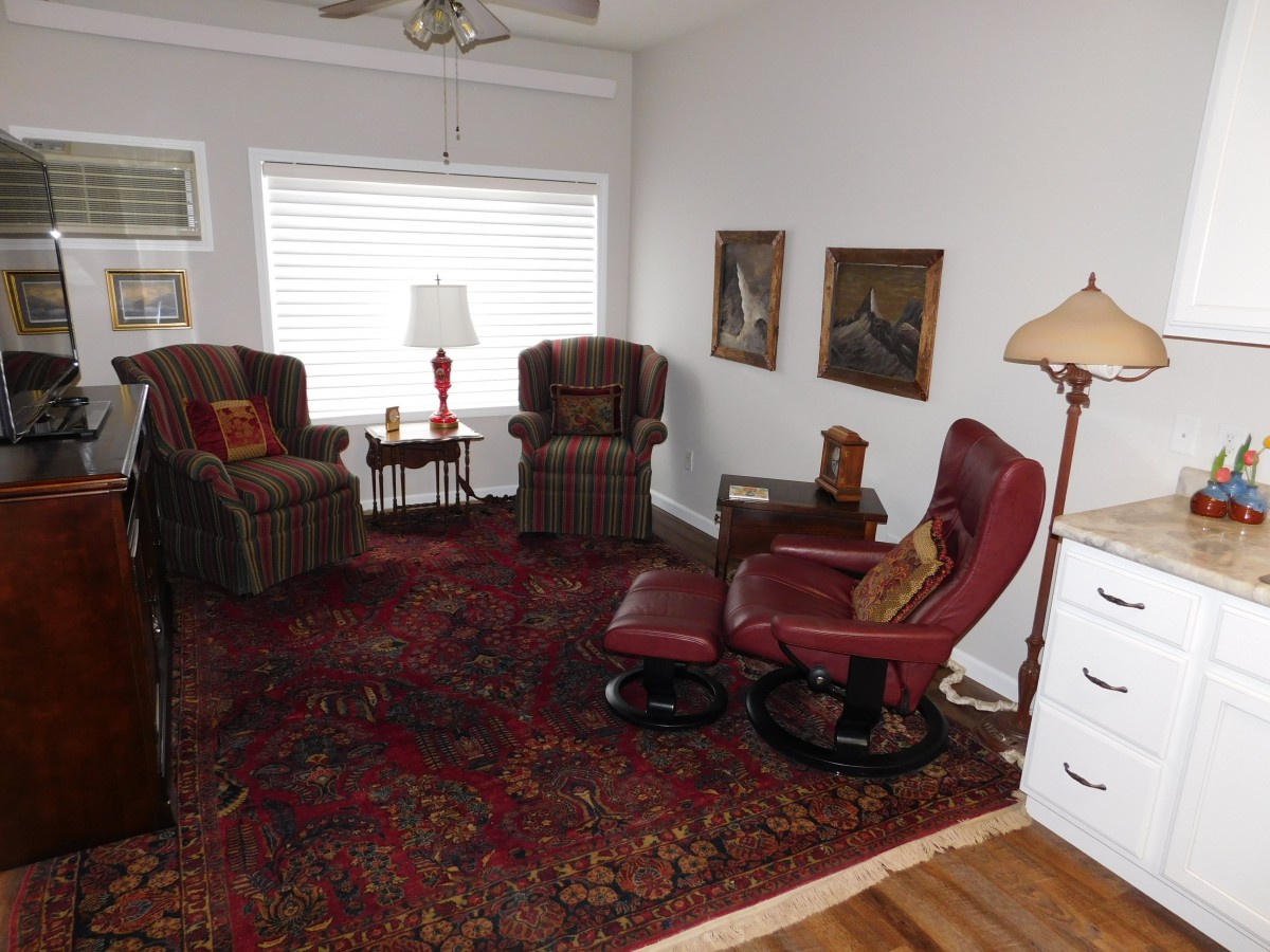 A cozy living room with armchairs, a red rug, and decorative lamps.