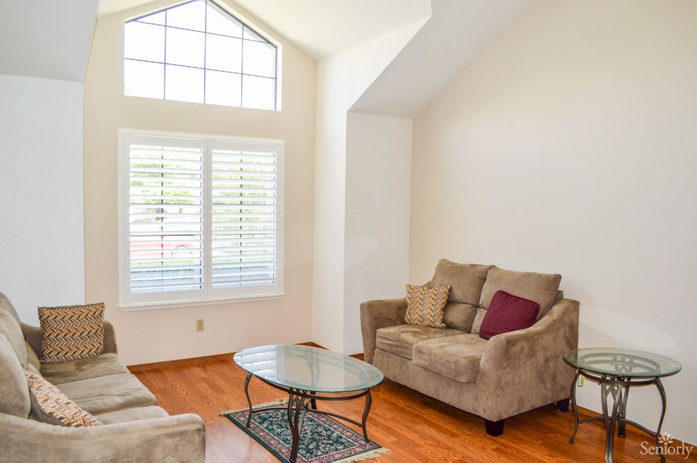 A cozy living room with a soft sofa, coffee table, and large windows letting in natural light.