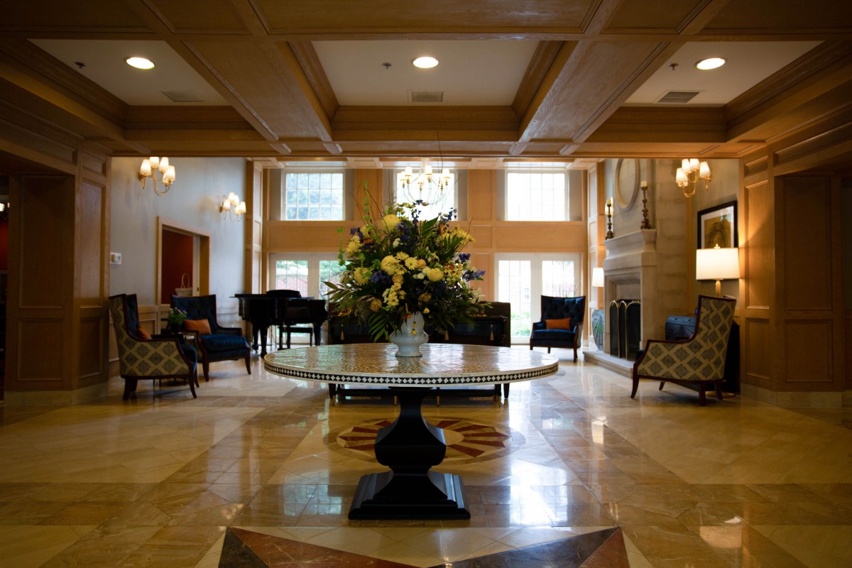 A spacious hotel lobby with elegant decor, featuring a central floral arrangement and comfortable seating areas.