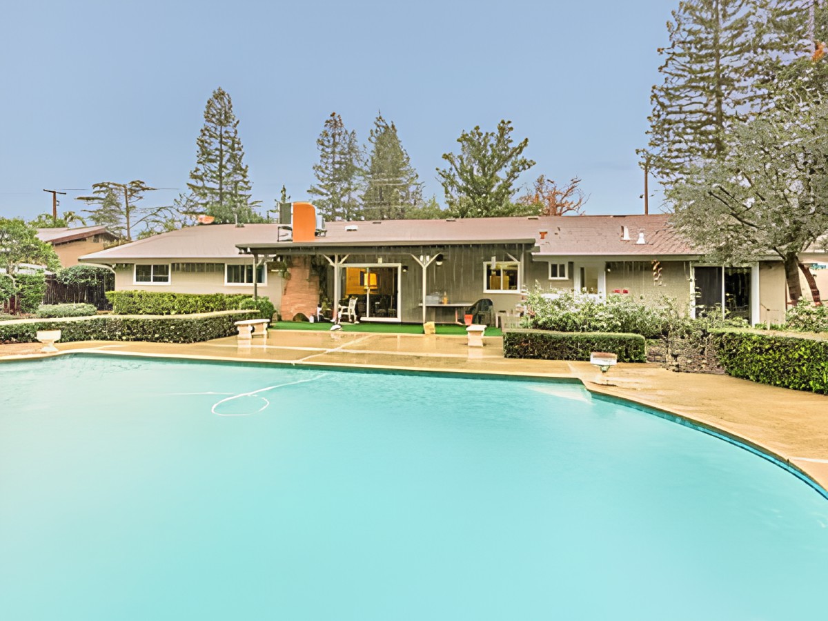 A serene backyard featuring a house with a pool and surrounding trees.