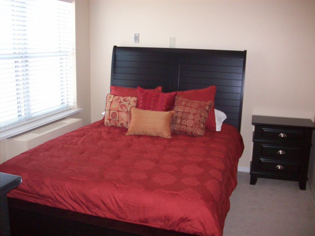 A cozy bedroom with a red bedspread and pillows.