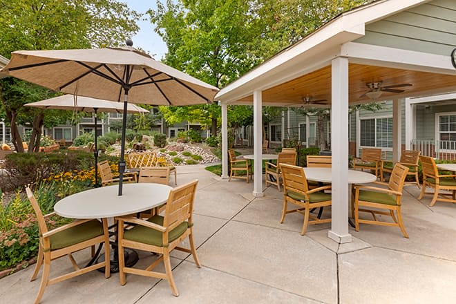 A serene outdoor patio area with tables, chairs, and umbrellas amidst lush greenery.