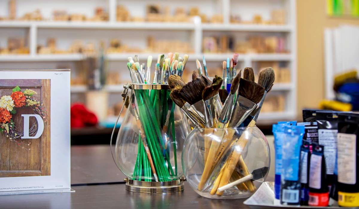 A collection of paintbrushes and pencils organized in glass holders in an art studio.
