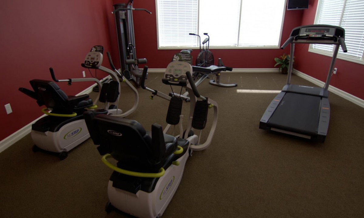 A fitness room featuring various exercise equipment including treadmills and elliptical machines.