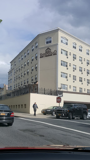A view of a hotel building from the street, with cars parked nearby.
